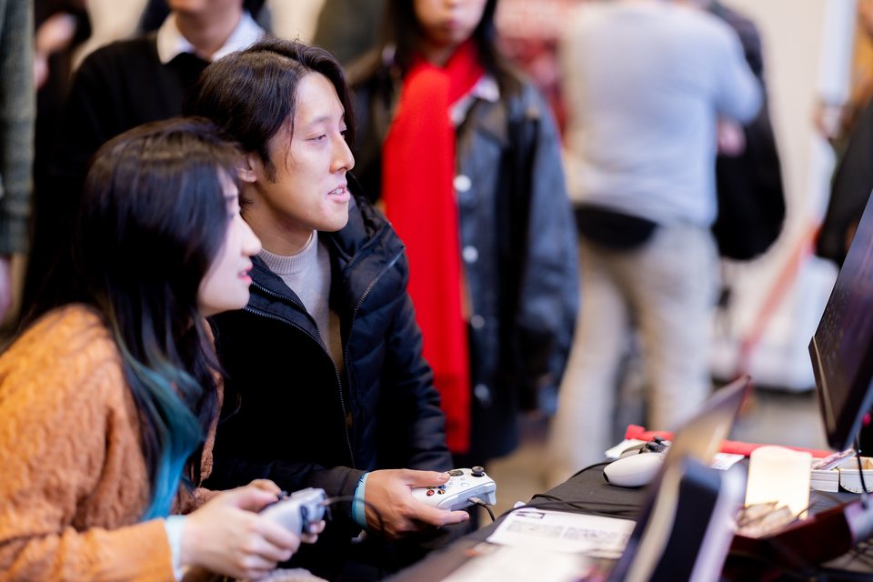 Two attendees playing on controllers in the Console Lounge